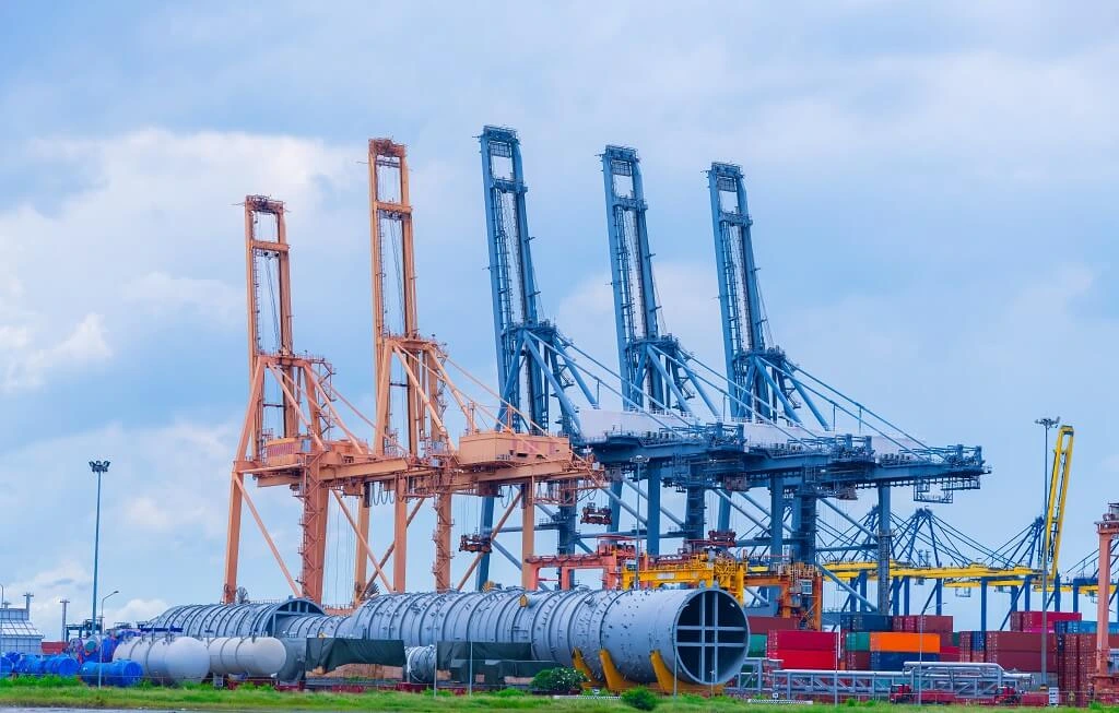 Project logistics in Singapore with cargo ship, trucks, and dock cranes at harbour terminal for shipment operations