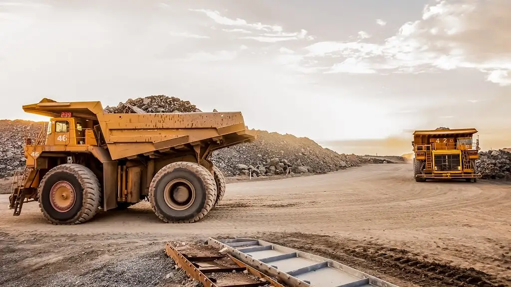 Heavy mining trucks at a rock quarry at sunset, supporting mining logistics in Singapore.